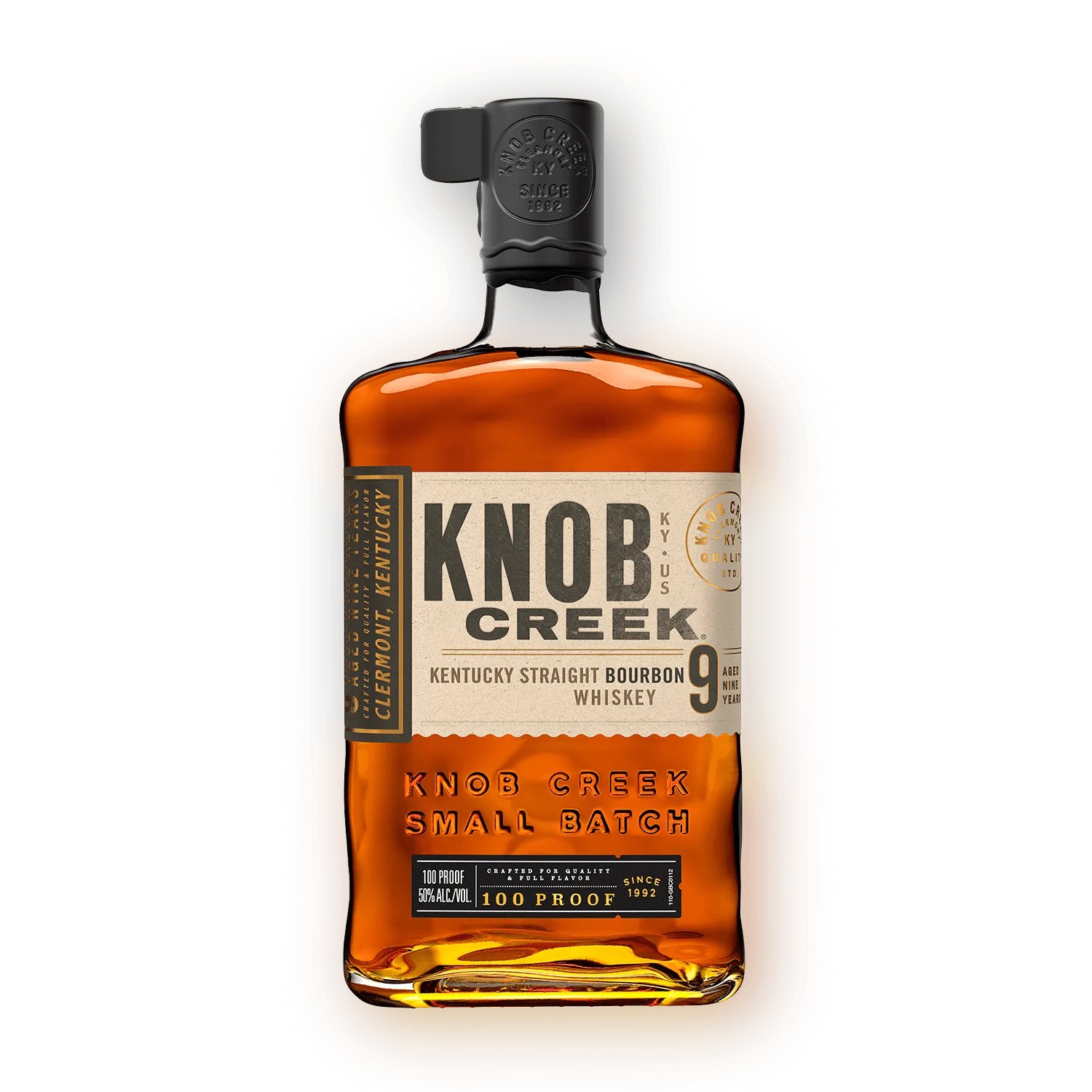 Dark bourbon in a glass beside an unmarked bottle, dramatic warm light